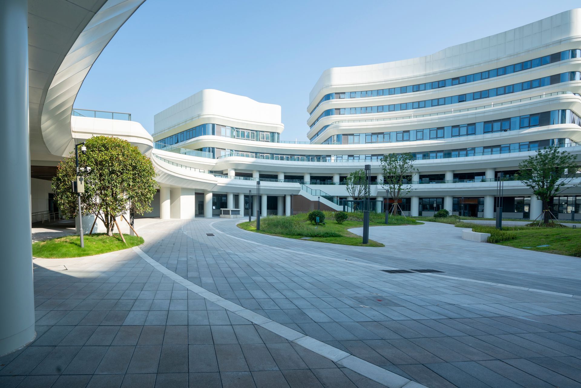 Modern white office complex with curved glass buildings and a wide paved courtyard