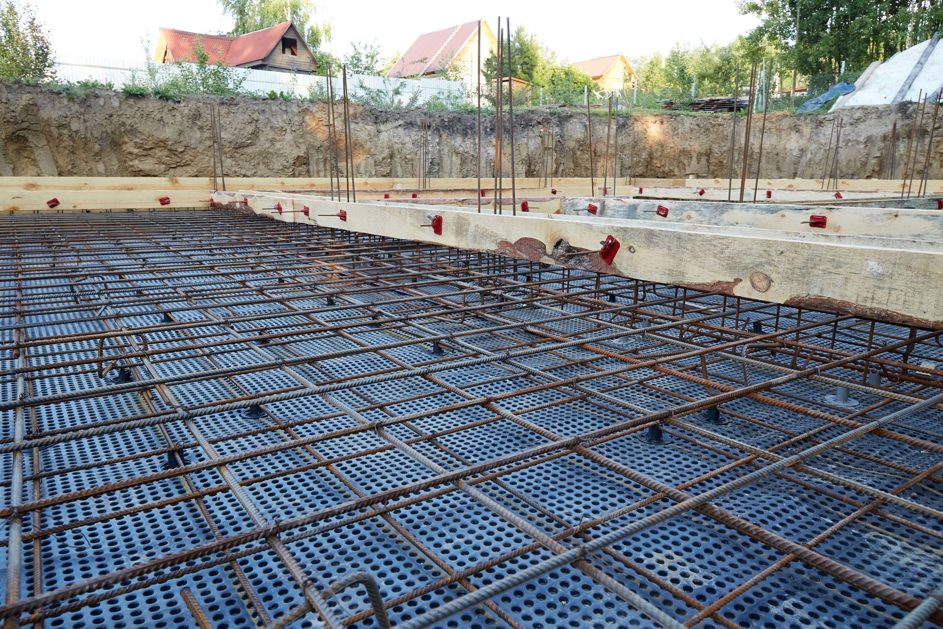 Rebar grid and blue formwork at a construction site with concrete foundation walls