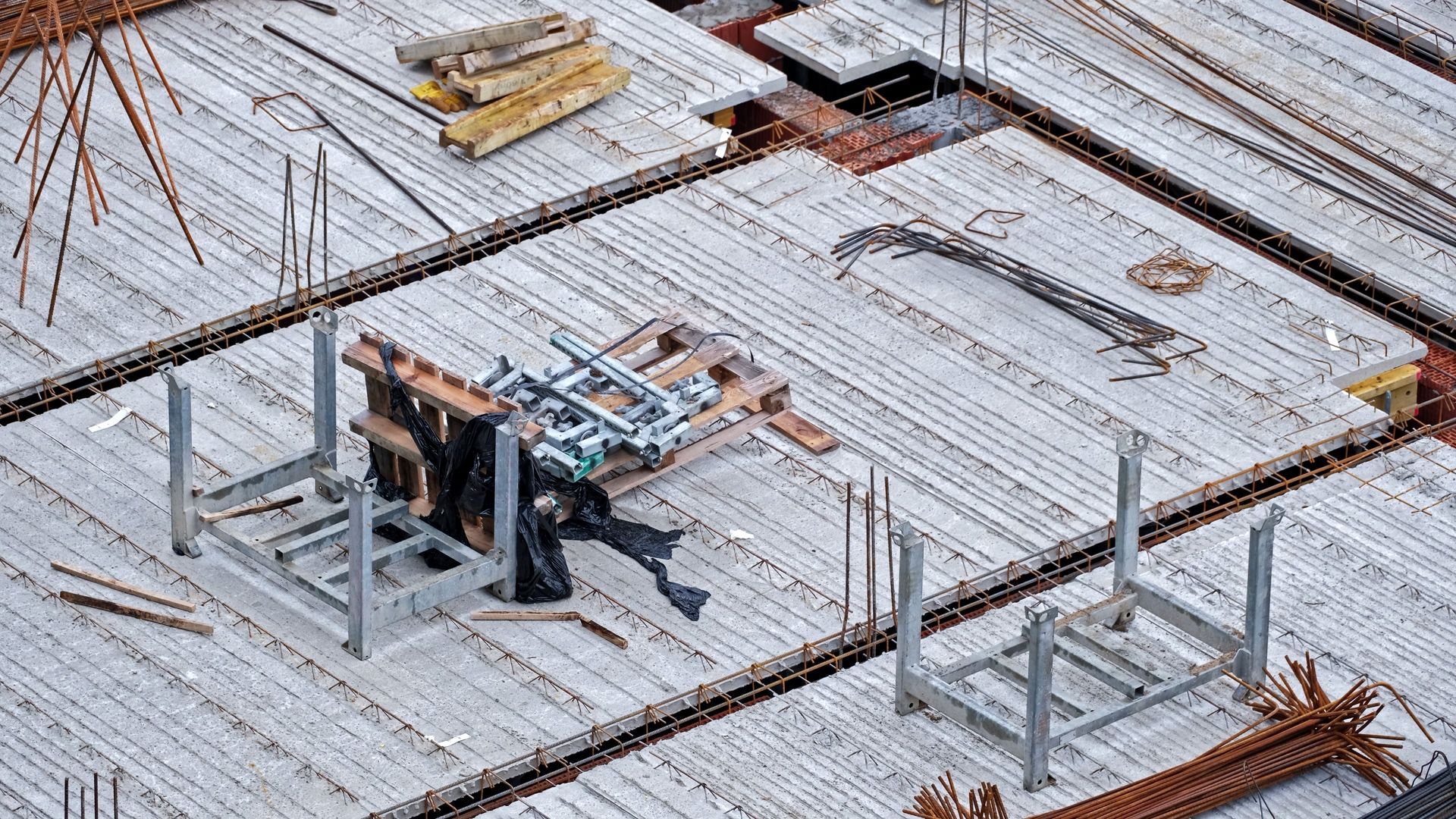 Construction site with concrete slab reinforcement and a rebar-bending machine on the floor