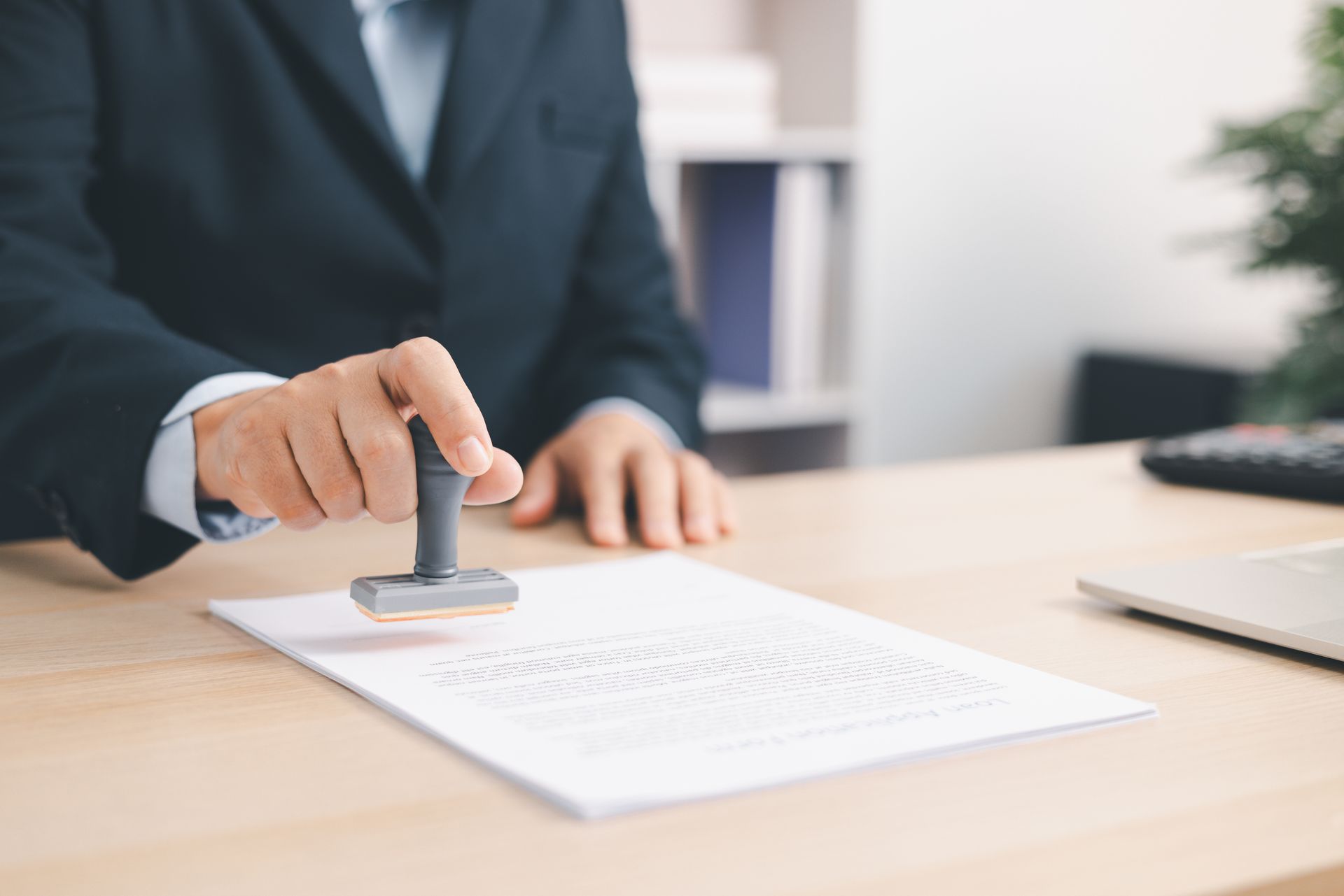 Hand stamping a document on a desk in an office setting