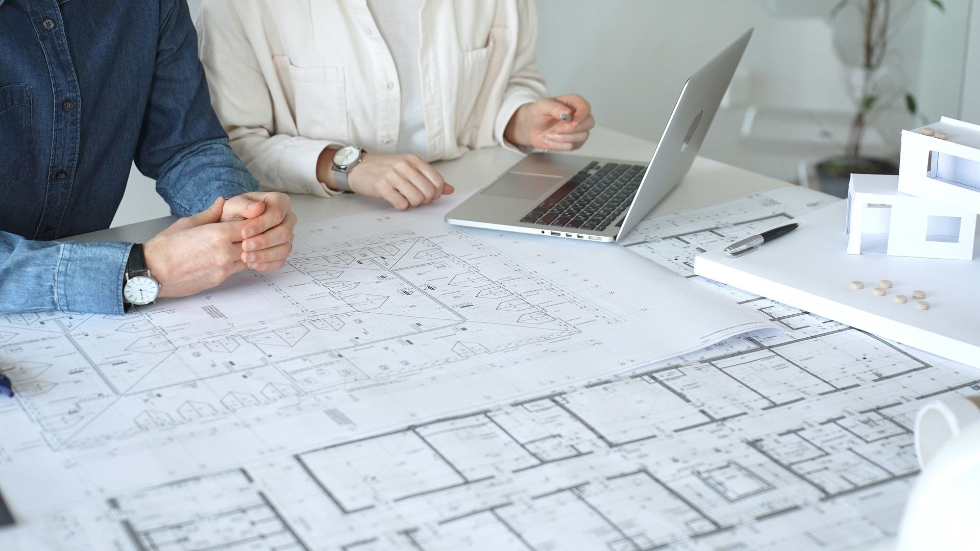 Team meeting over architectural blueprints with a laptop on a white table