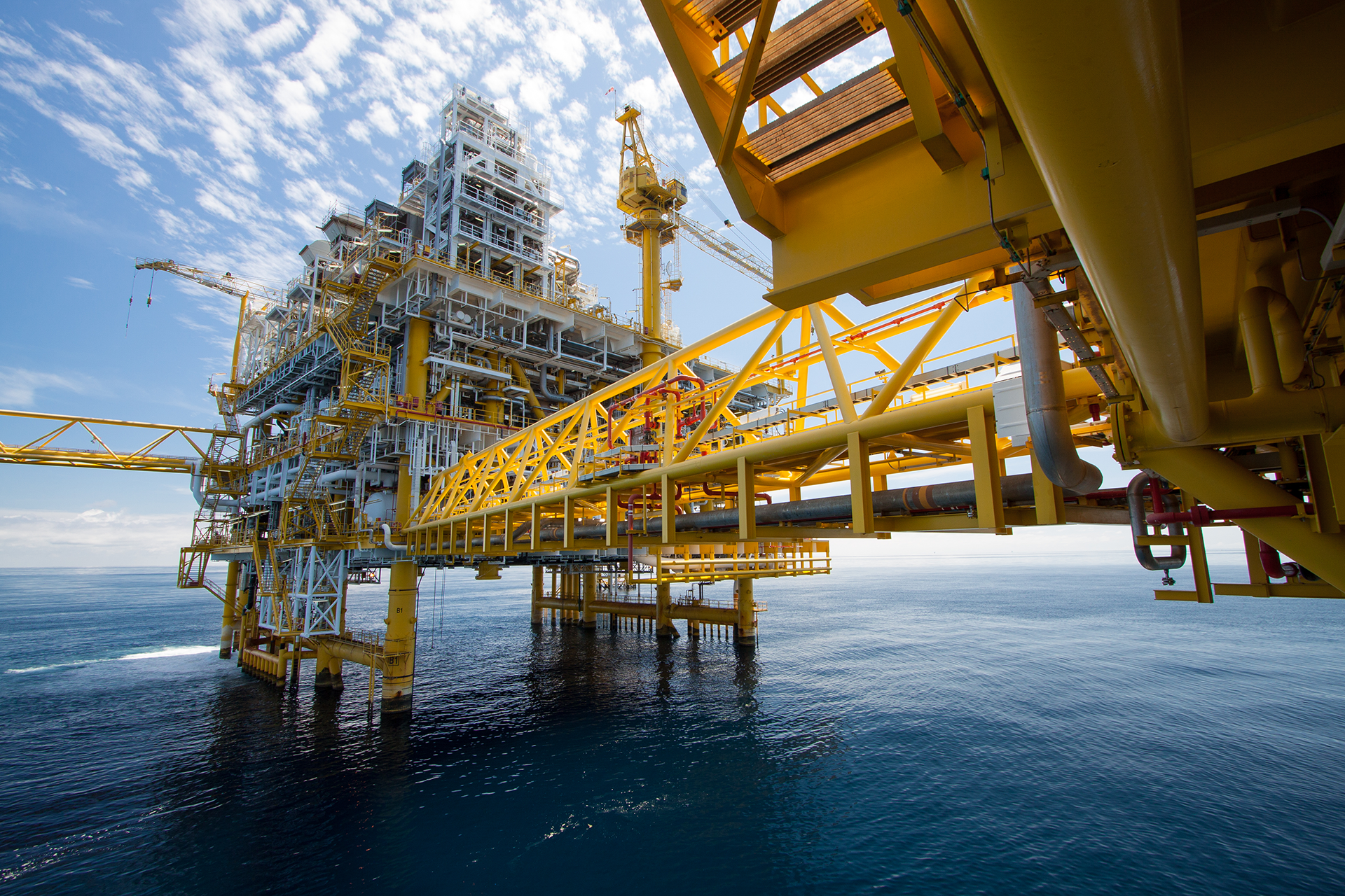A large yellow oil rig in the middle of the ocean.