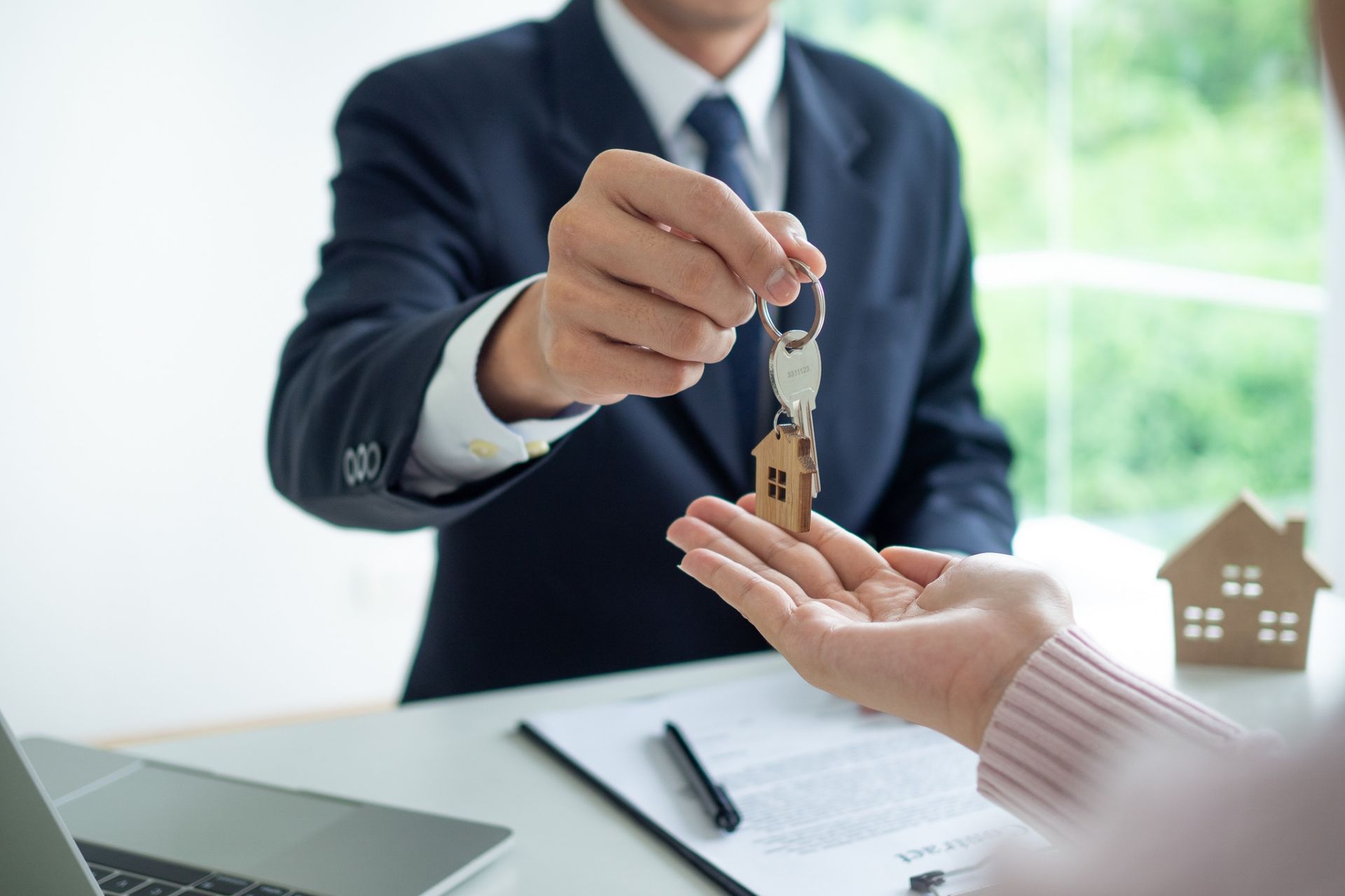 Businessperson handing over house keys during a real estate signing at a desk
