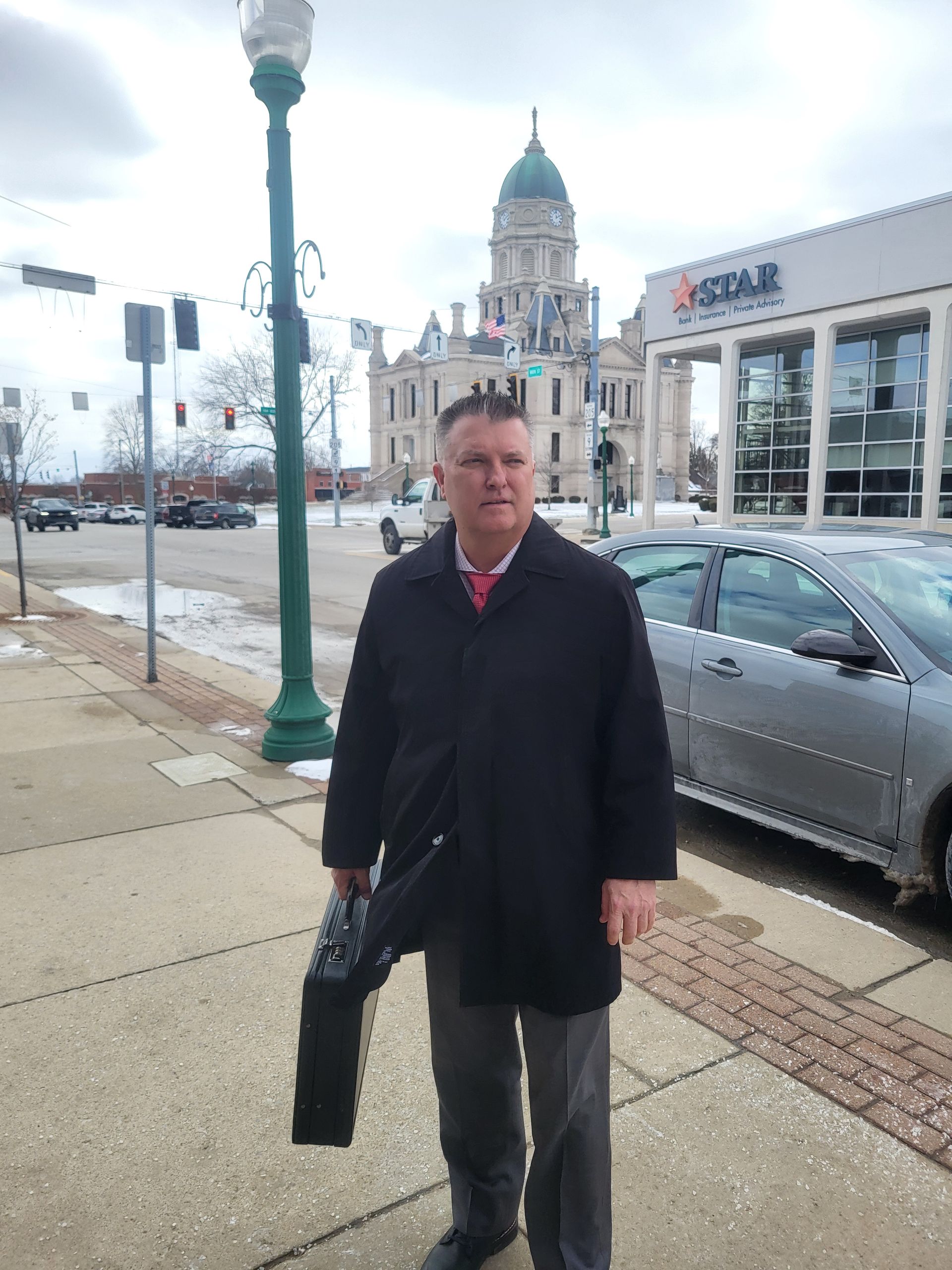 Brad Baber, attorney near Fort Wayne, standing outside in his suit in front of the Whitley County Courthouse.