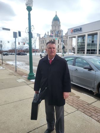 Brad Baber, attorney near Fort Wayne, standing outside in his suit in front of the Whitley County Courthouse.