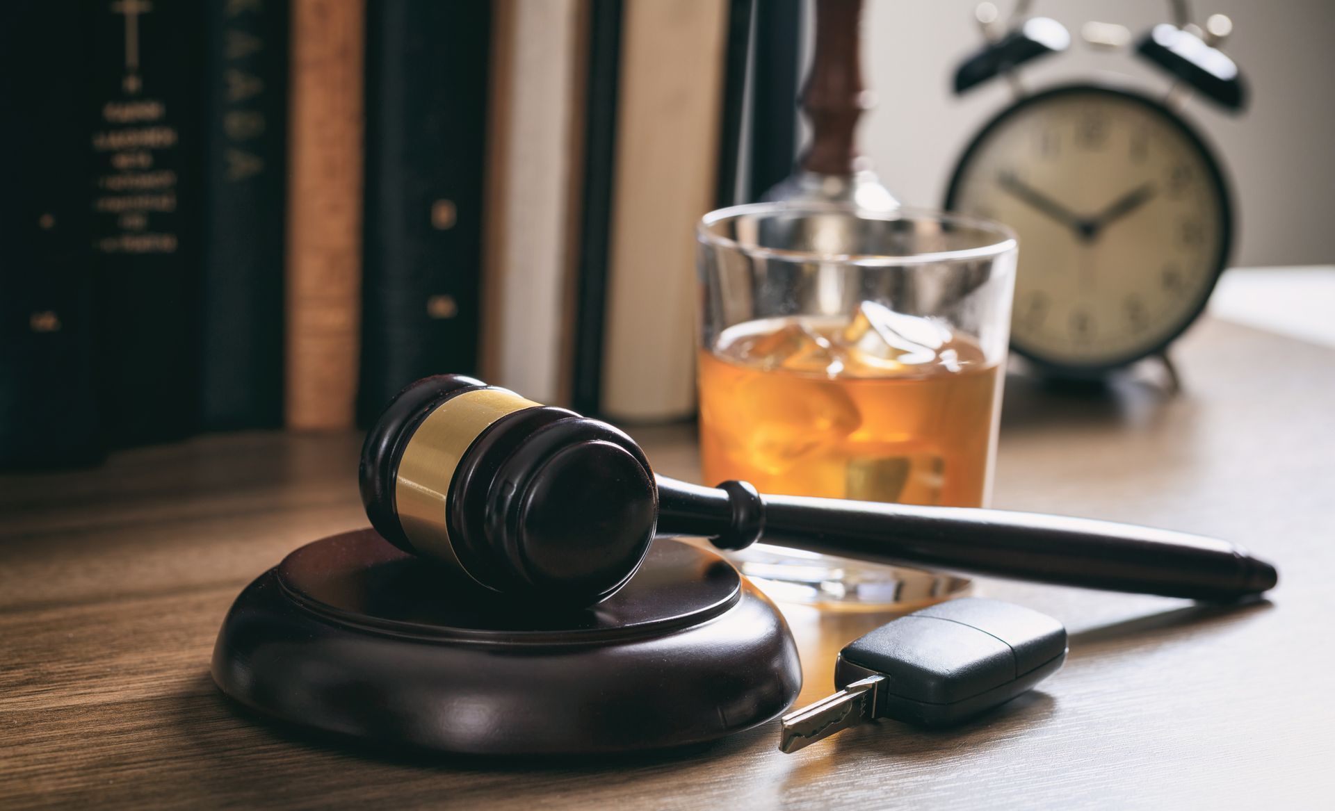 Alcohol and car keys on a wooden desk.