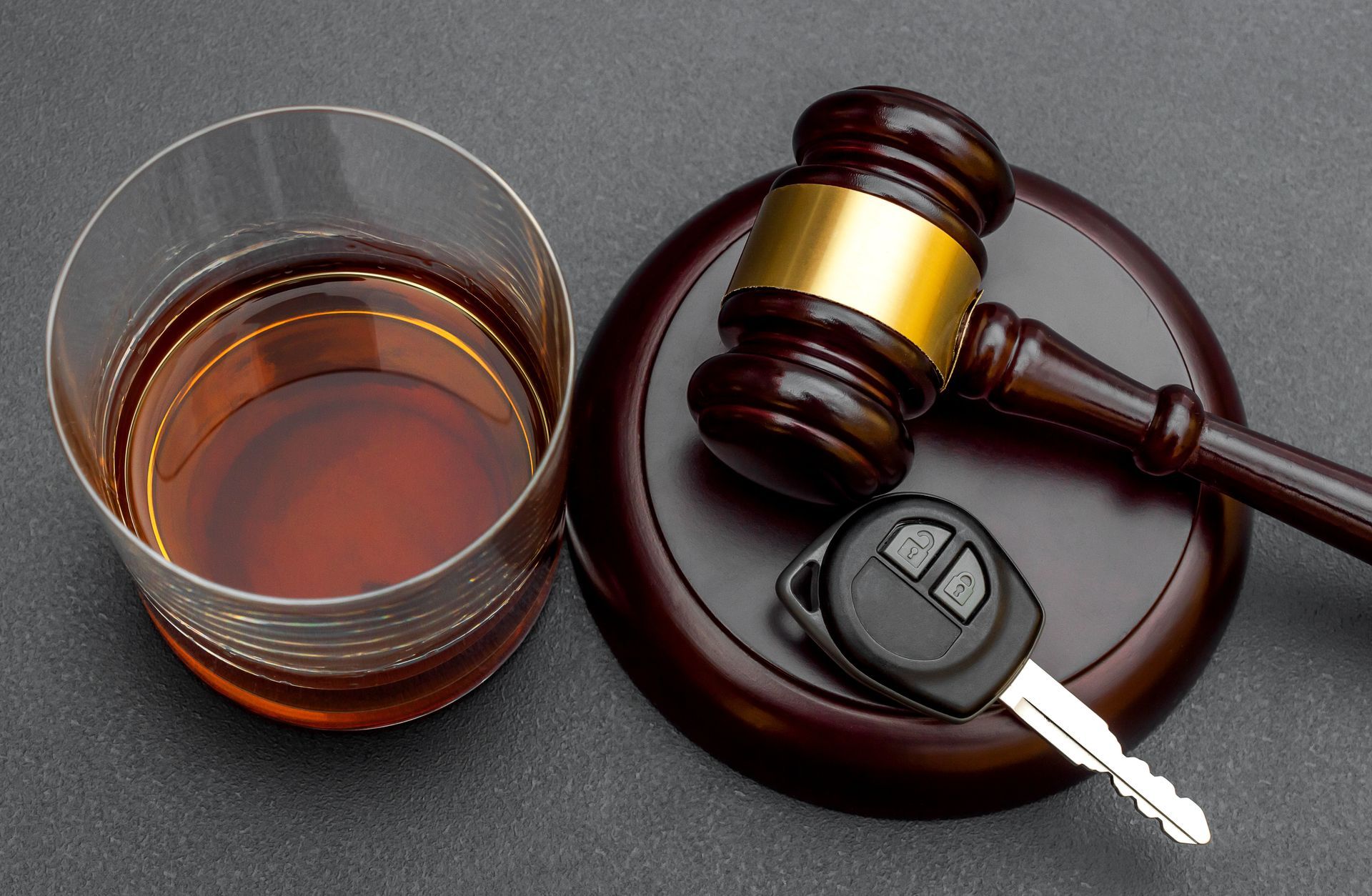 Judge's gavel with car key and glass of whiskey on black. Judge's gavel with car key and glass of whiskey on black.