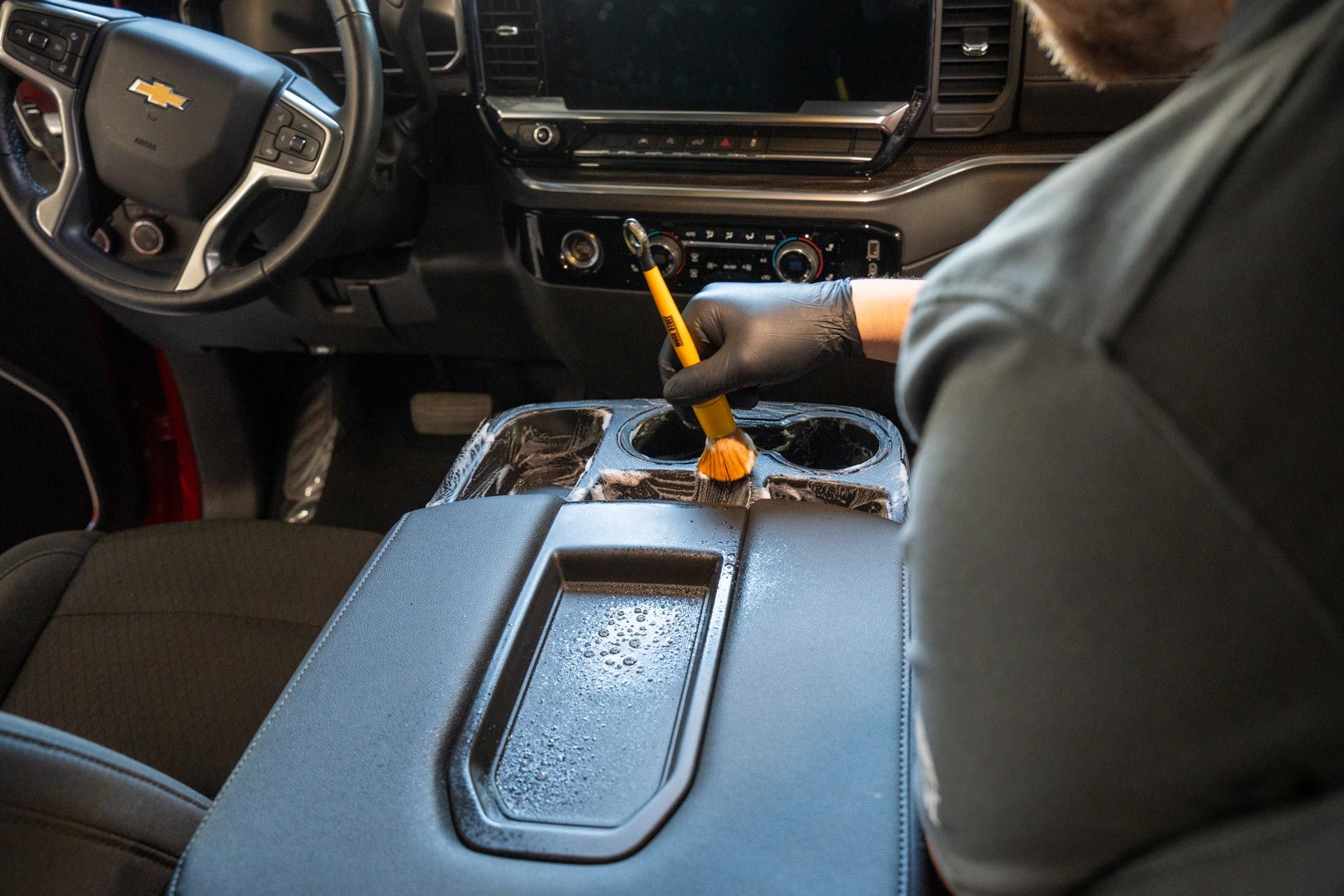 A person is cleaning the interior of a car with a steam cleaner.