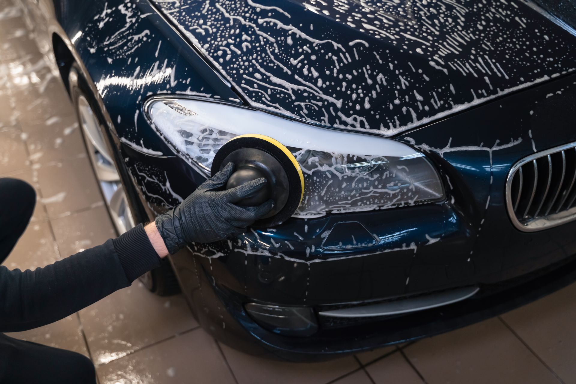 A person is polishing the headlight of a car.