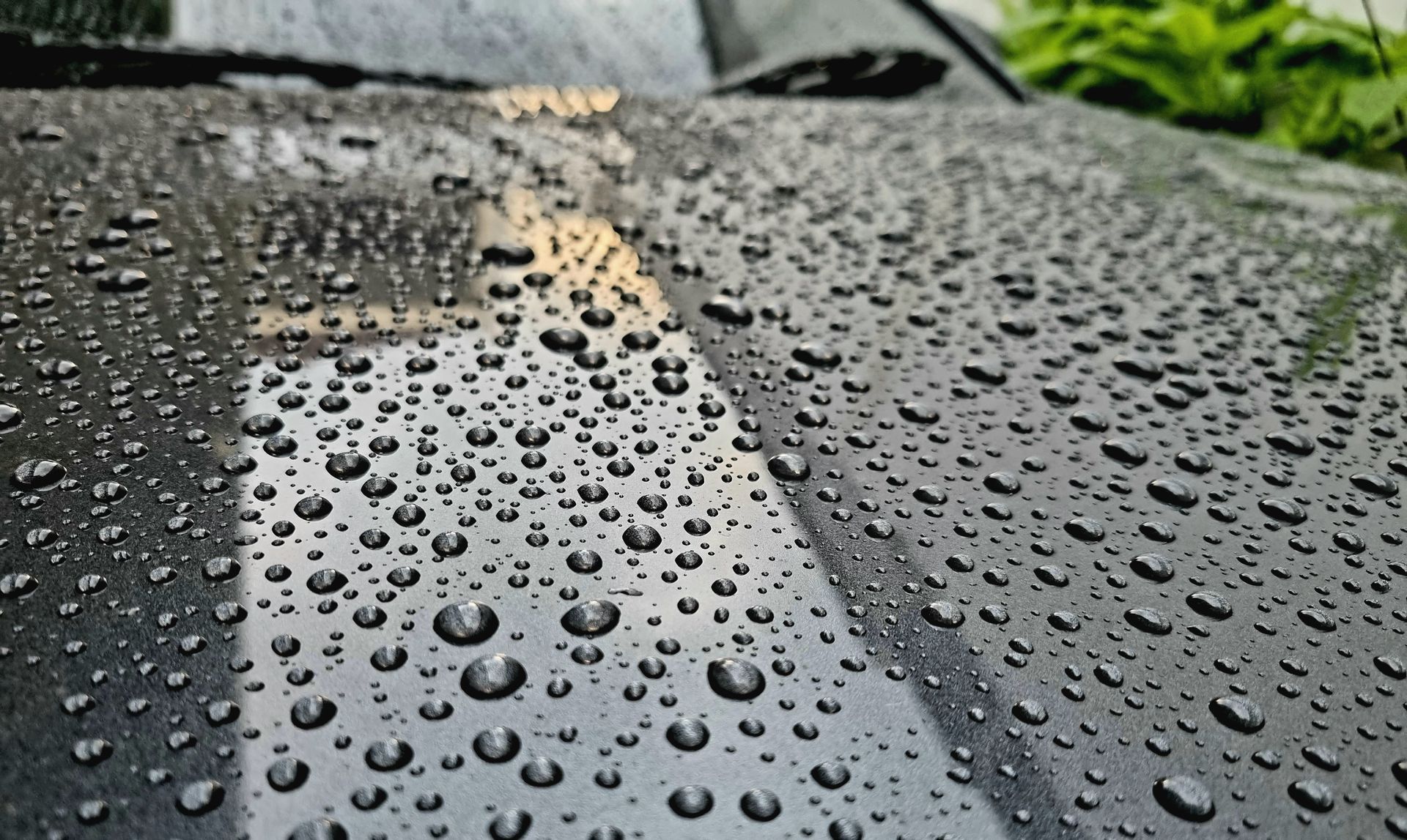A person is cleaning a black car with a yellow cloth.