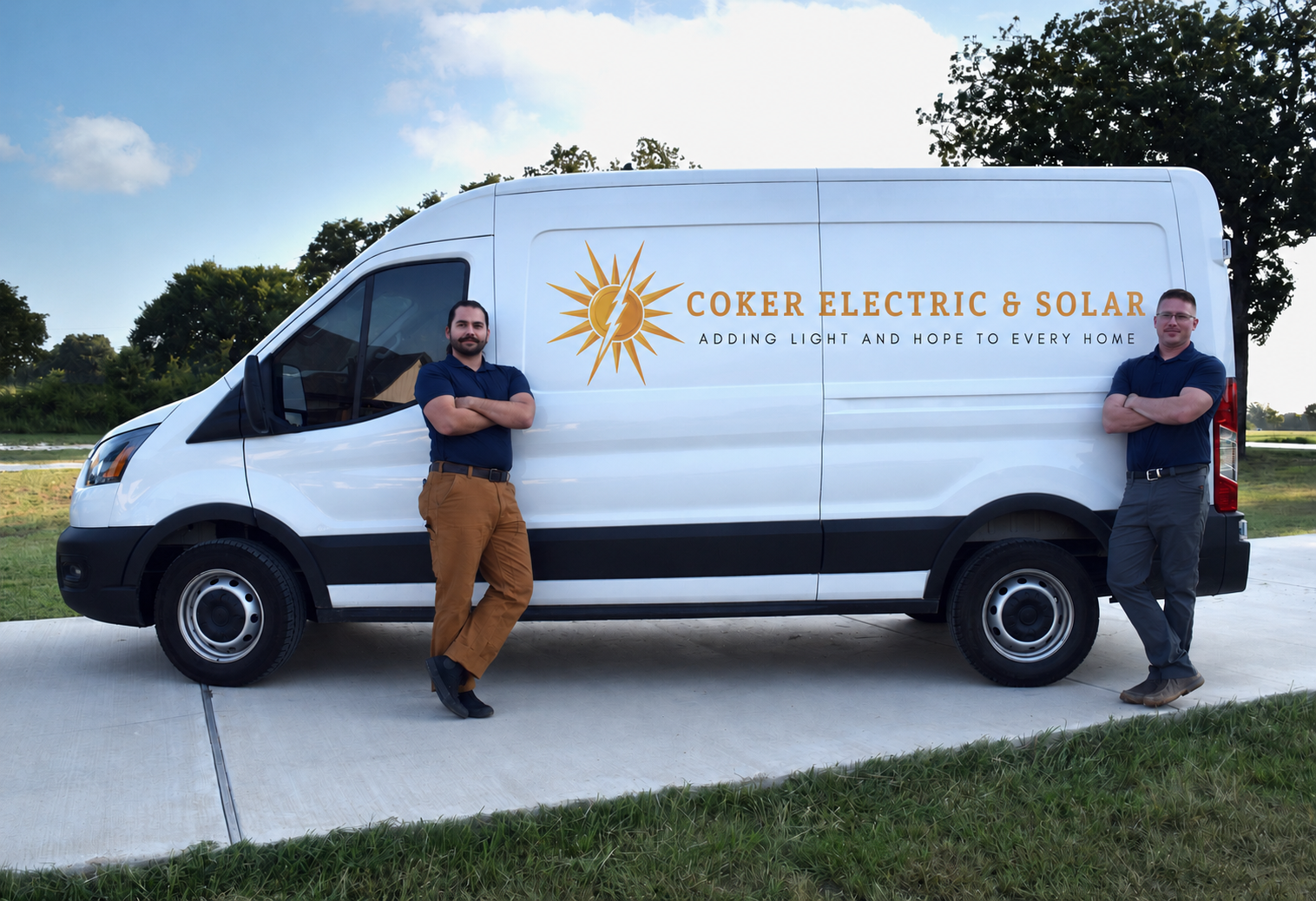 Two men stand beside a white Coker Electric & Solar van outdoors.