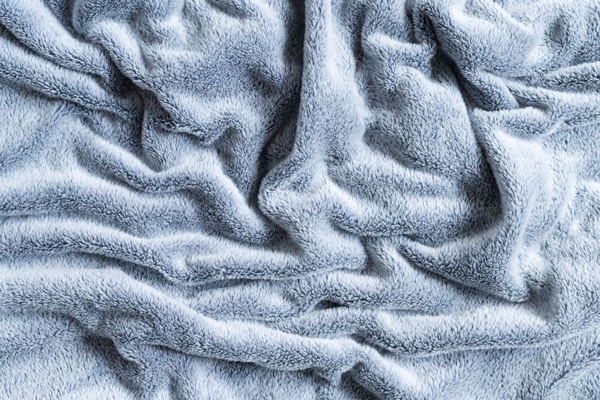 Primo piano di una superficie di tessuto stropicciata di colore grigio-azzurro chiaro.