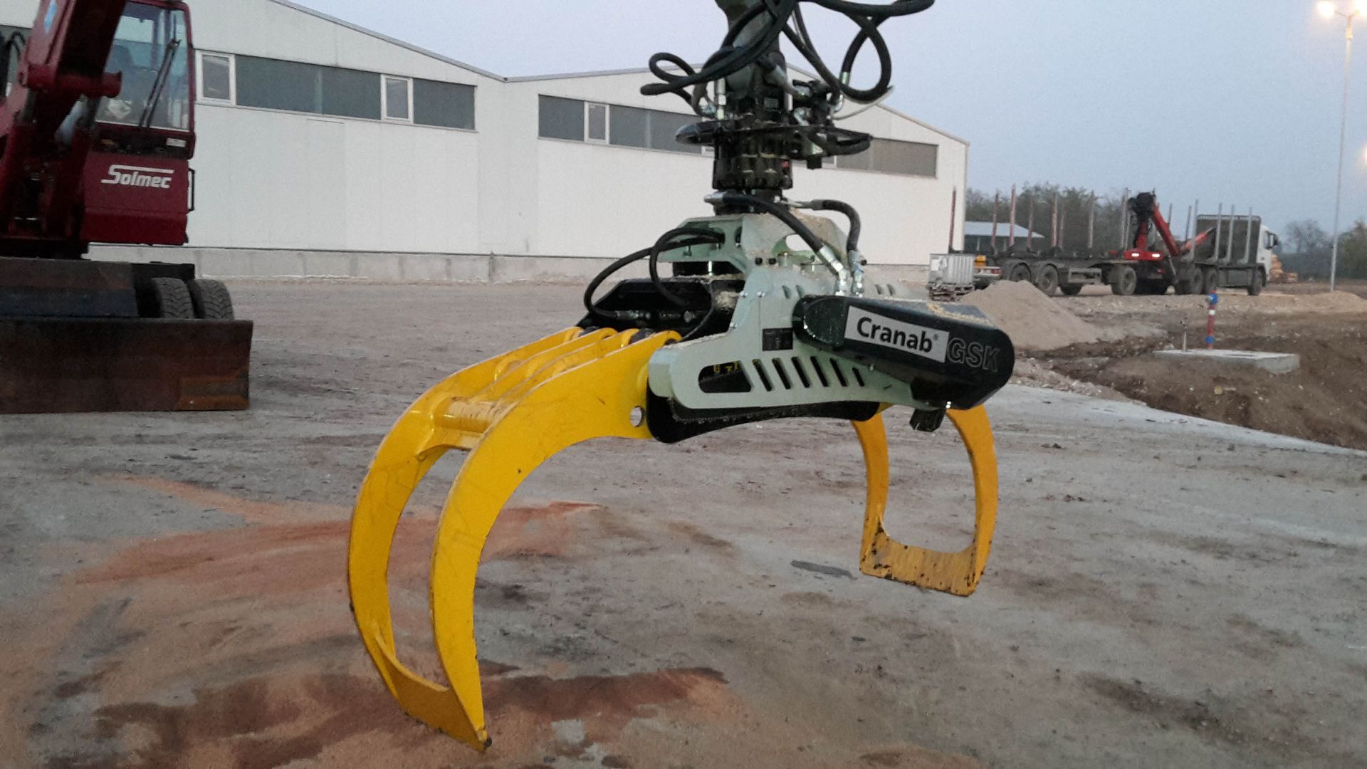 Braccio di presa giallo su un escavatore, tenuto aperto in un cantiere edile all'aperto.