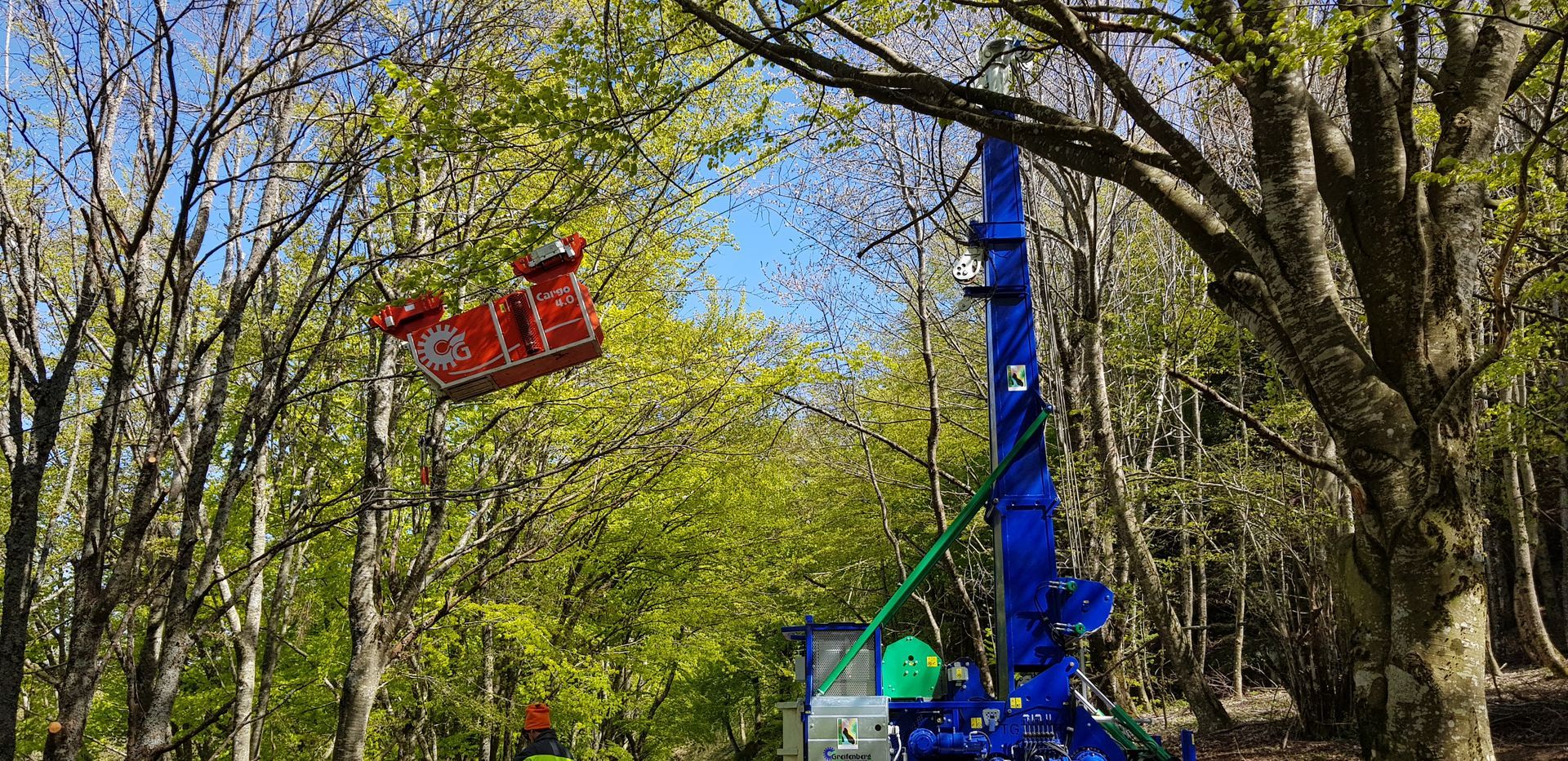Un'attrazione blu e rossa in un parco divertimenti in una zona verde e boscosa.