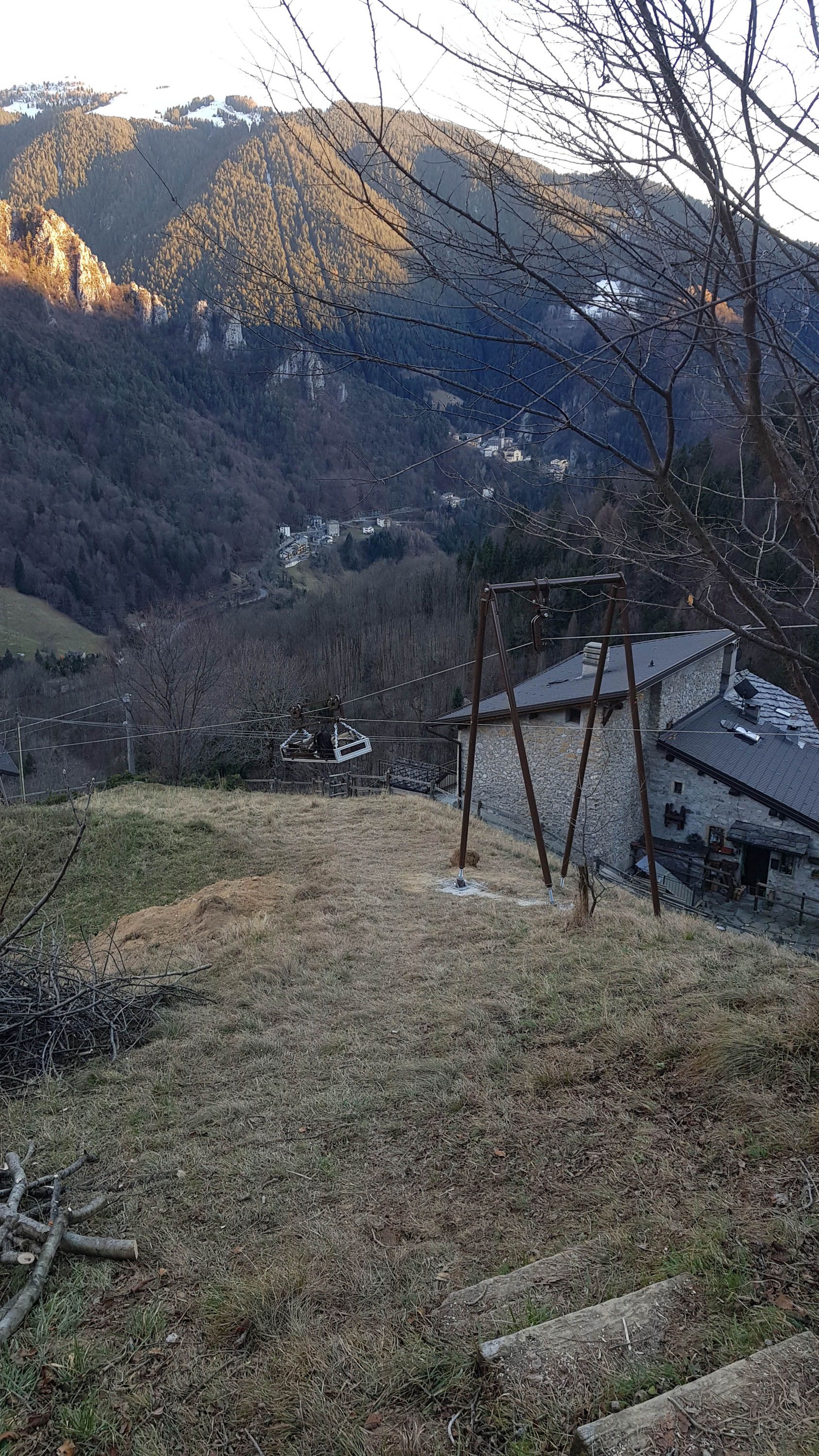Casa in pietra in una valle, alberi e montagne sullo sfondo.