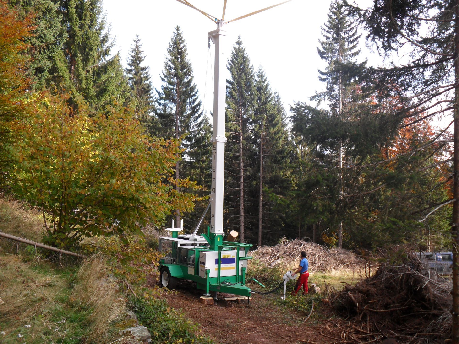 Una turbina eolica mobile ecologica in una radura nella foresta. Una persona lavora nelle vicinanze.