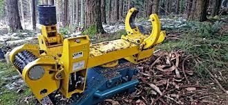 Una macchina forestale gialla in un ambiente boschivo, con alberi sullo sfondo.
