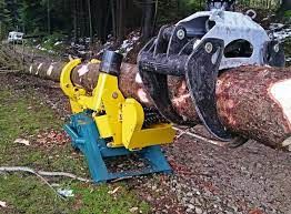 Uno spaccalegna giallo e blu che spacca un tronco tenuto da una pinza in una foresta.