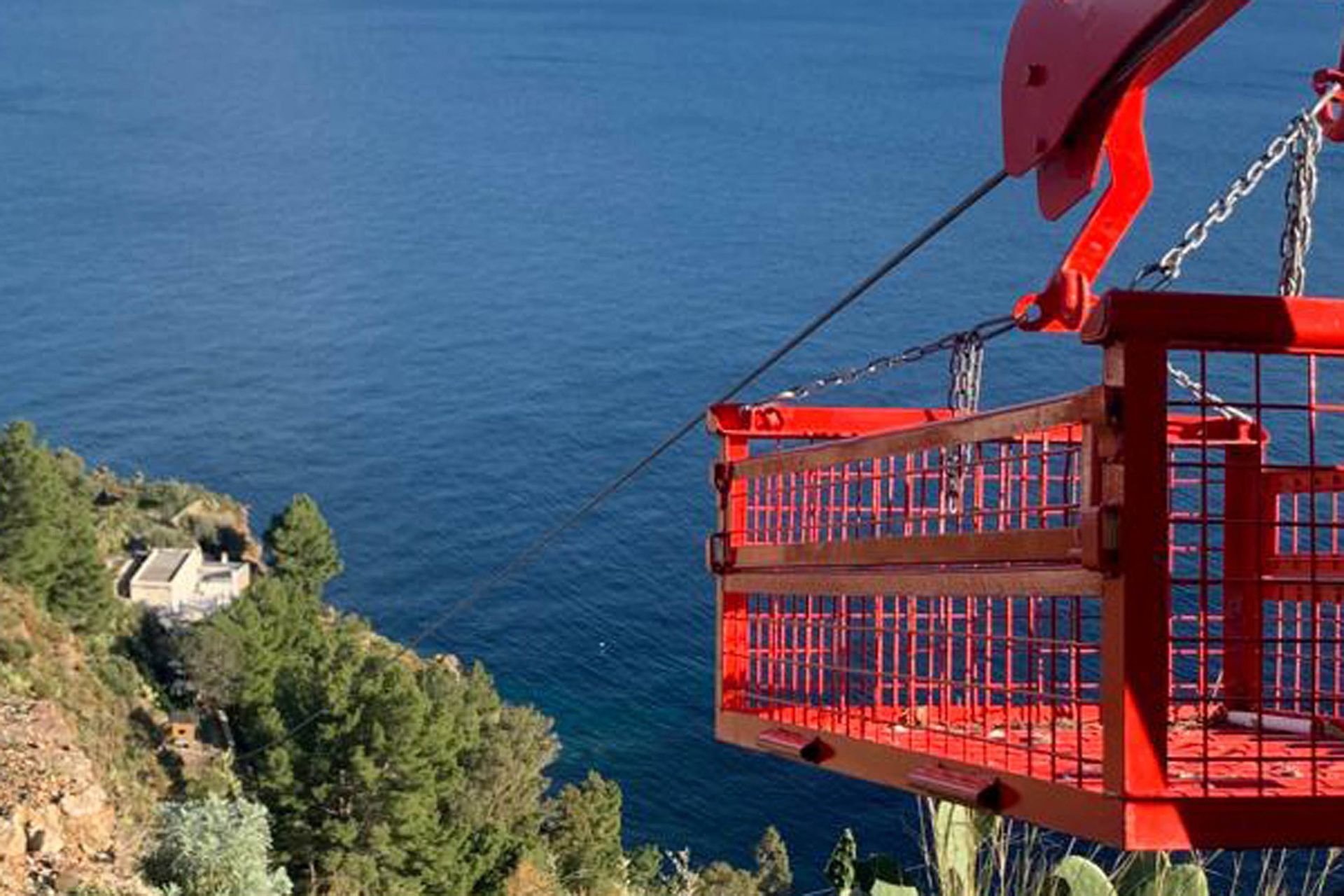 Cestello rosso della piattaforma aerea con vista sull'oceano e sulla costa.