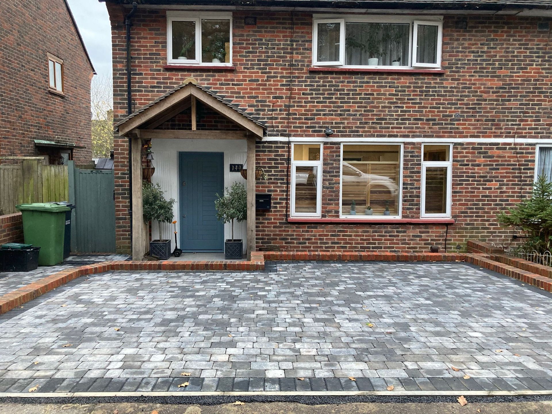A brick driveway leading to a house surrounded by trees and bushes.