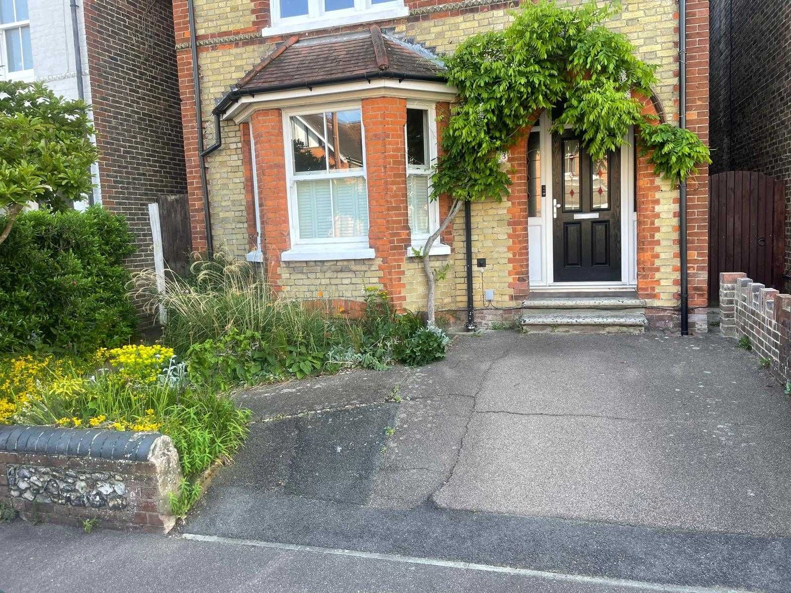 Brick driveway being paved with red and gray cobblestones beside a brick house.