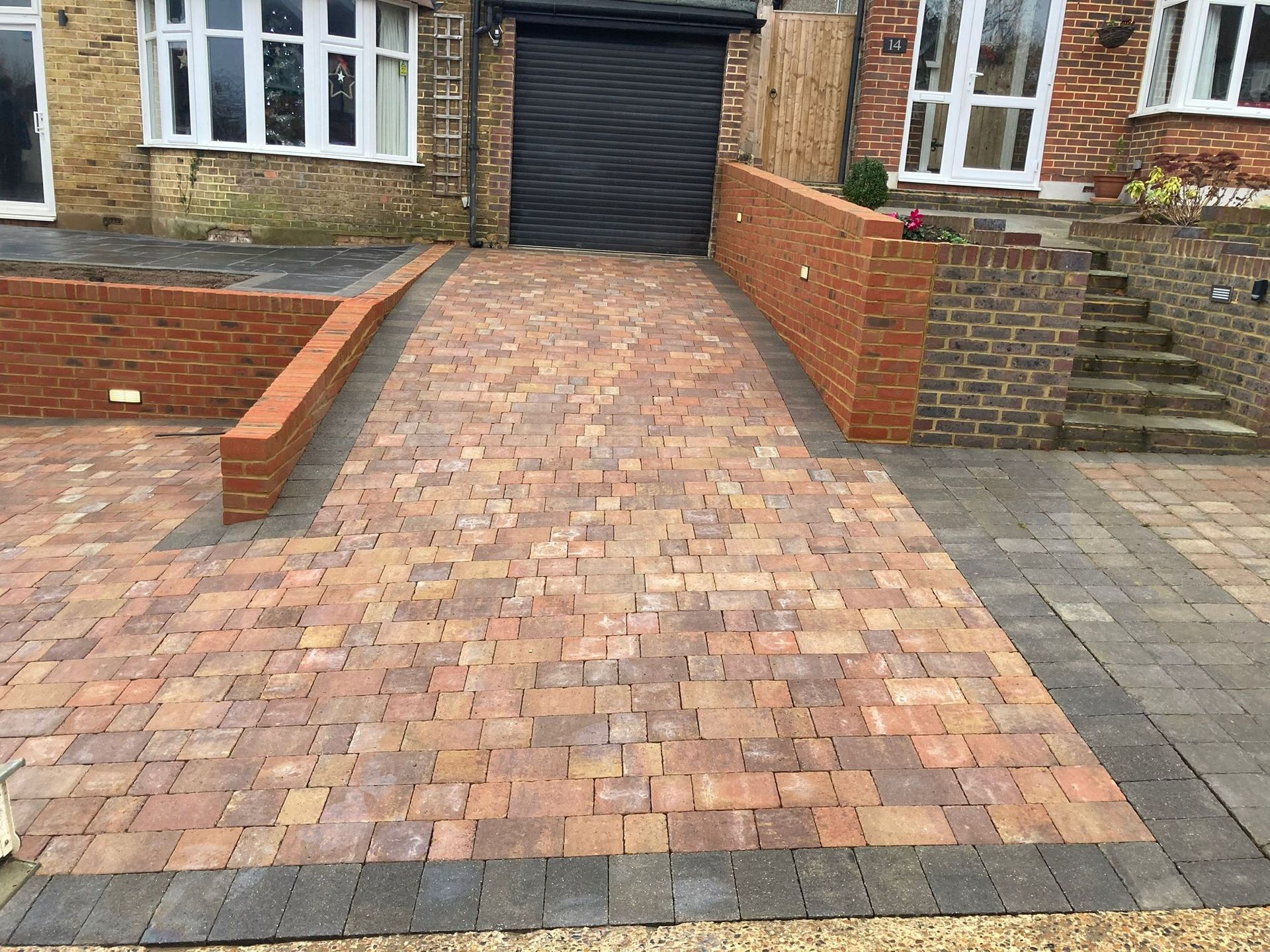 A brick driveway leading to a garage next to a brick wall.