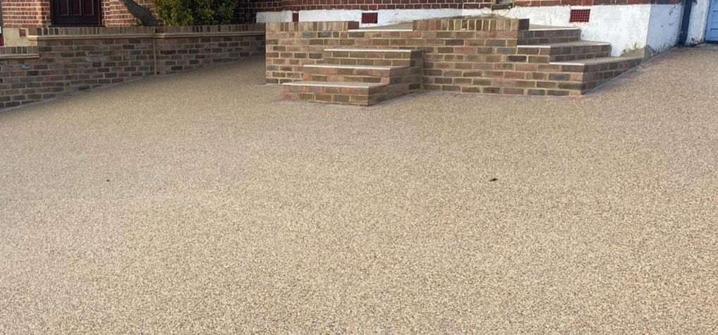 A resin driveway with stairs and a brick wall in front of a house.