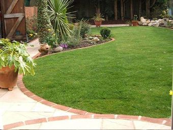 A lush green lawn with a brick walkway surrounding it