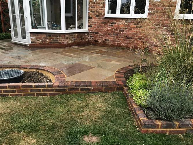 A brick house with a patio and a fountain in front of it.