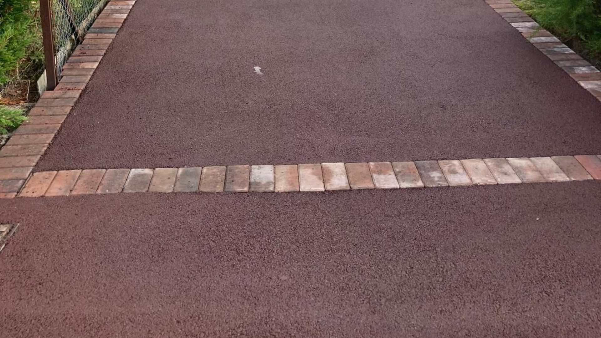 Dark red asphalt pathway with brick border and a brick section across the middle.