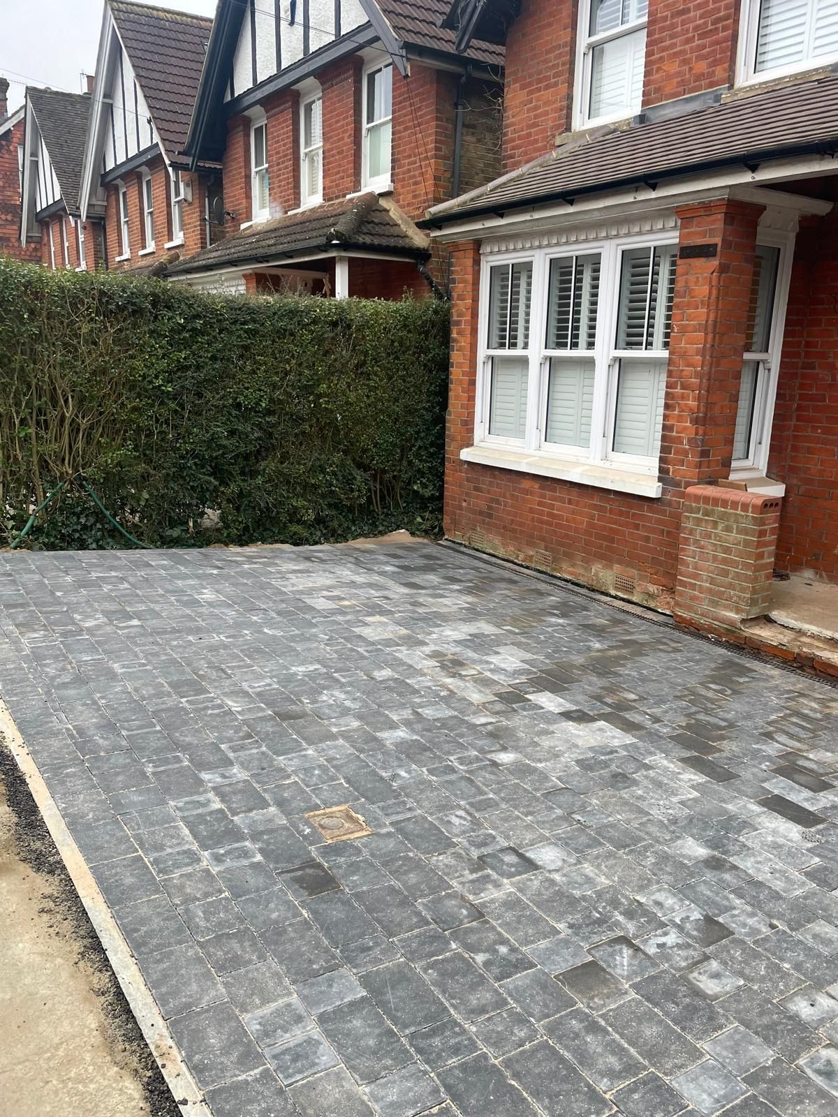 A brick house with a brick driveway in front of it.