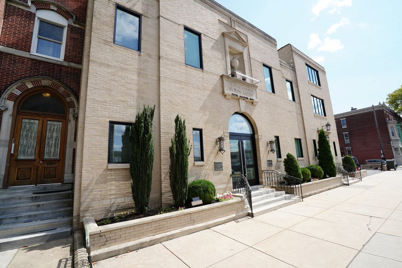 A large brick building with a lot of windows and trees in front of it.