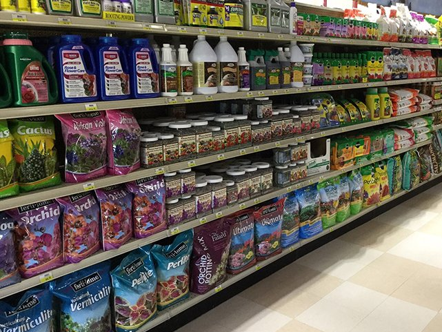 Shelves stocked with various gardening products, including fertilizers, soils, and plant food.