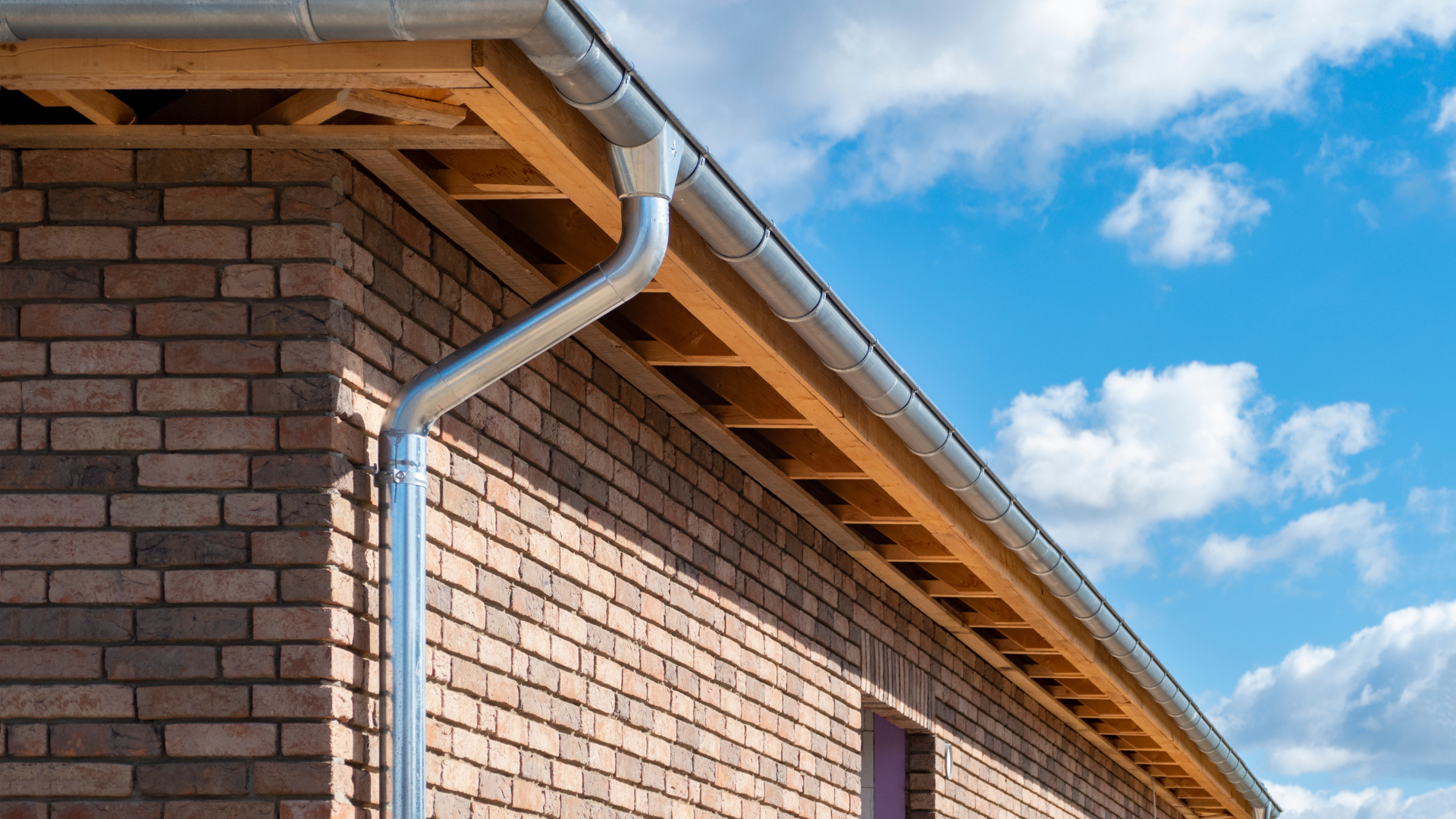 A brick building with a gutter on the side of it.