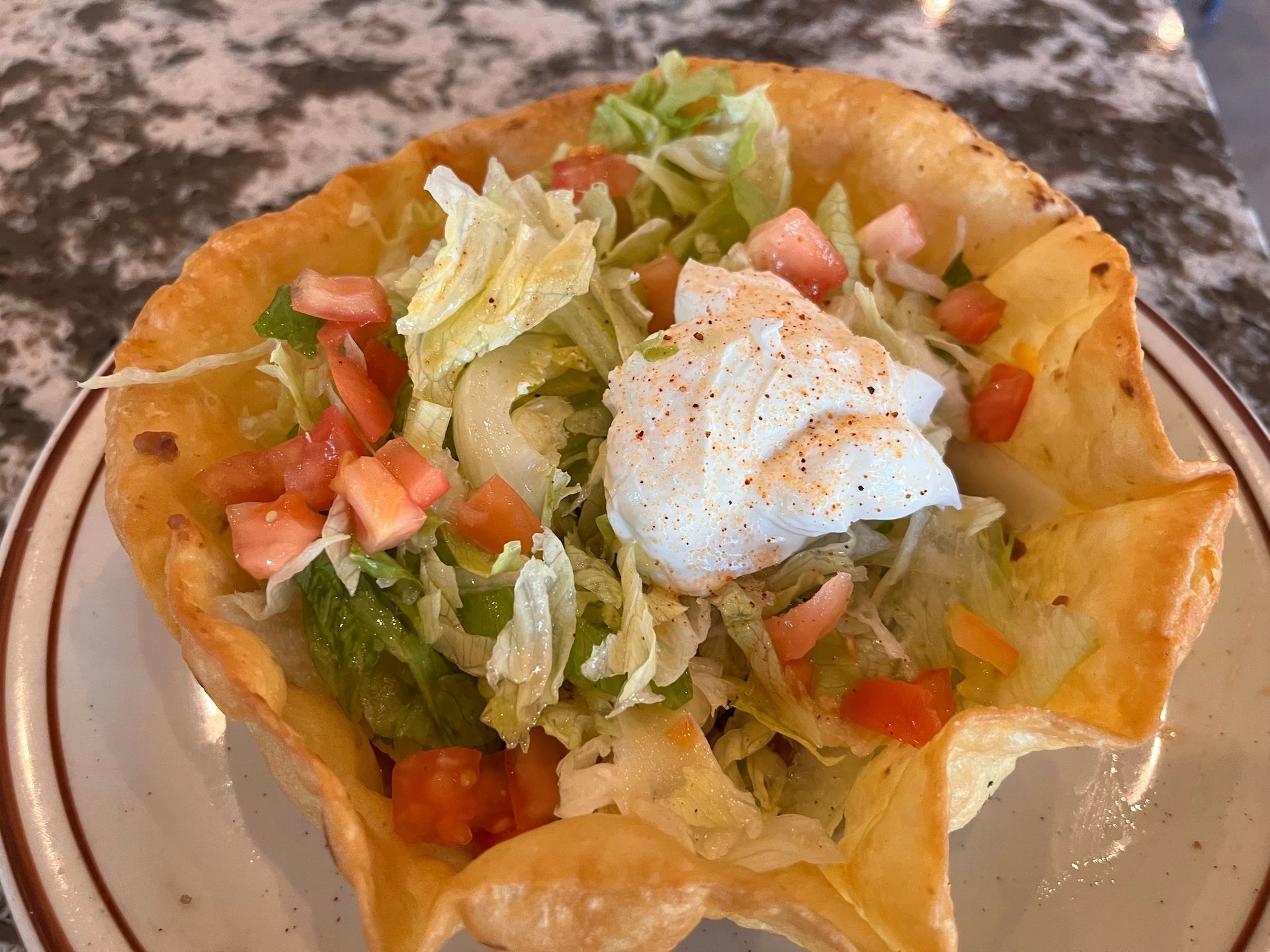 A close up of a taco salad on a plate on a table.