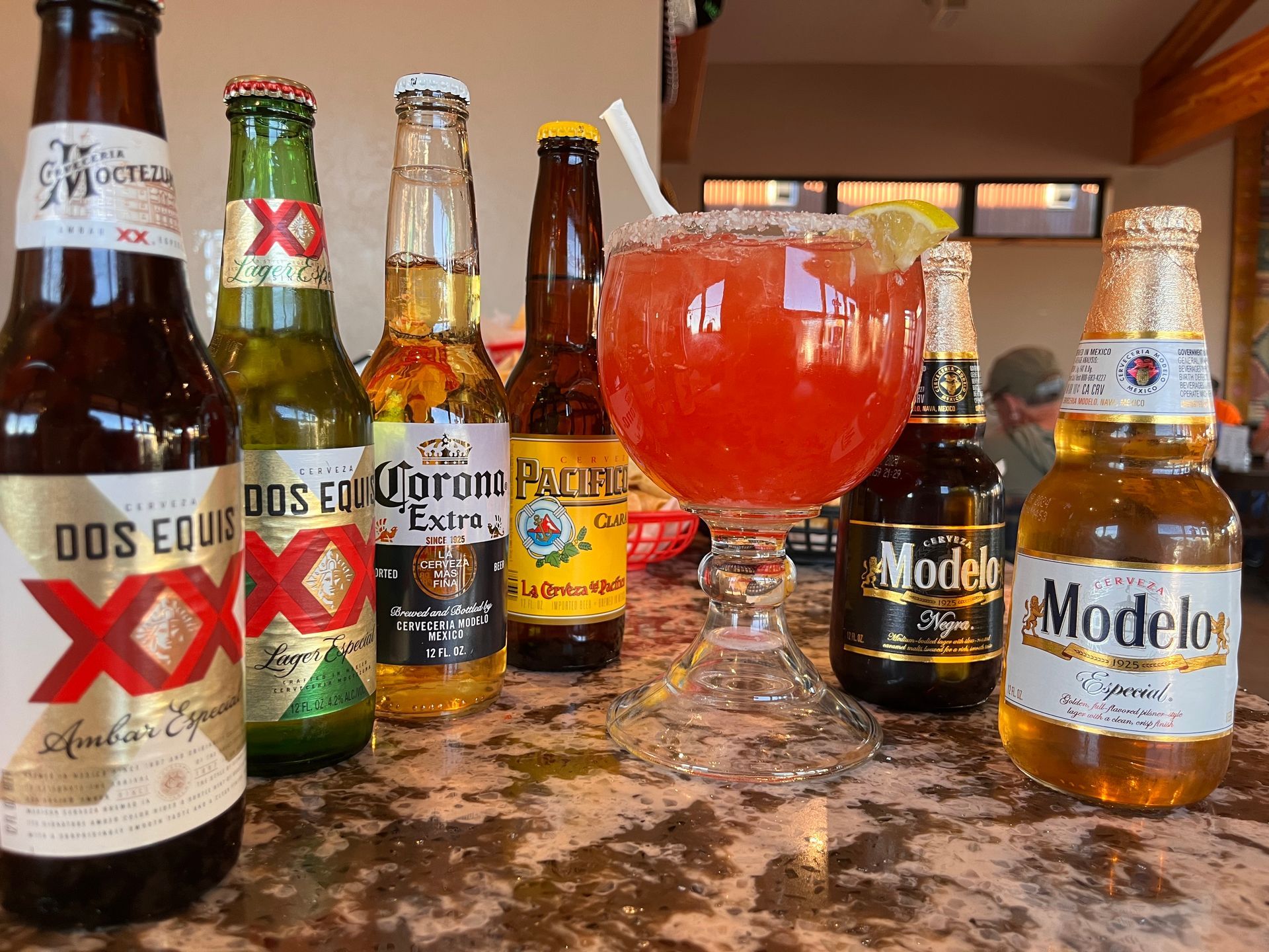 Several bottles of beer and a margarita on a table