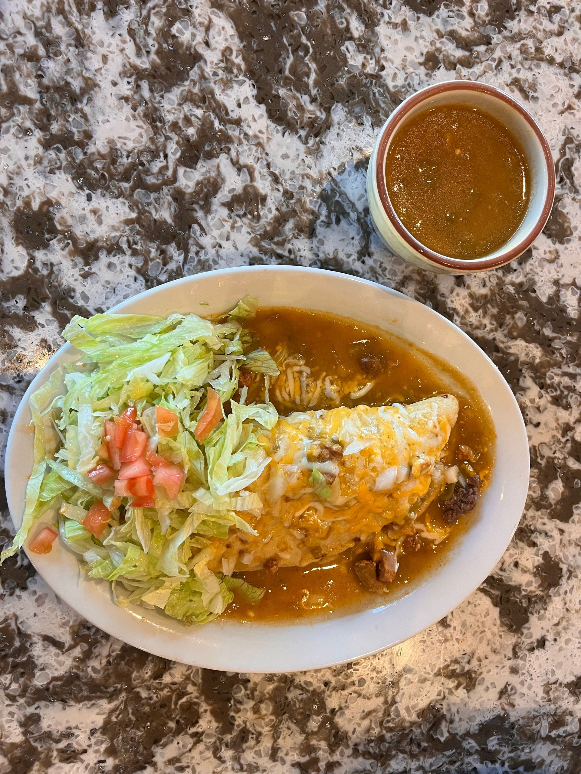 A plate of food with a bowl of sauce on a table.