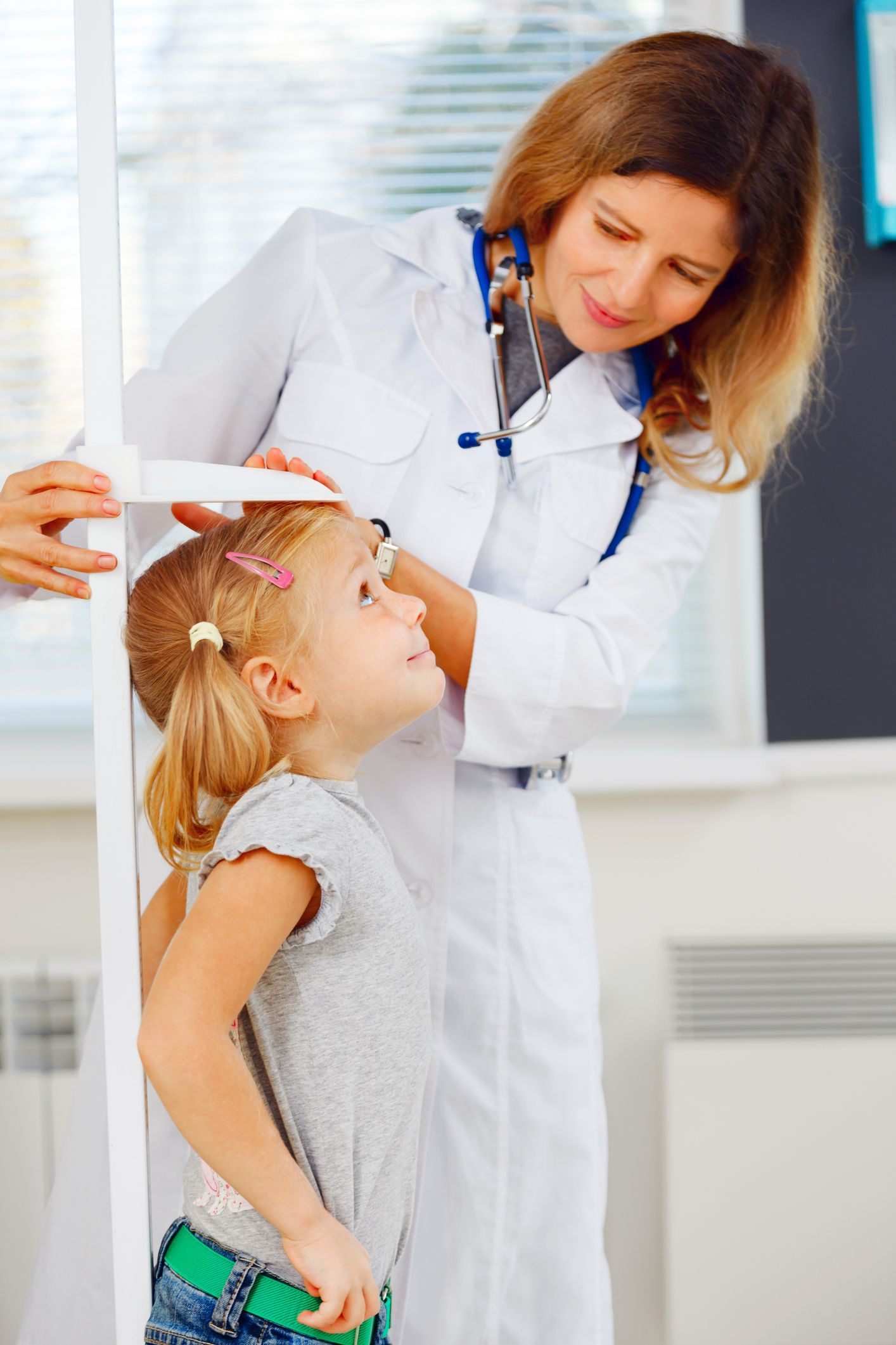 Doctor examining a child’s head with a hand mirror in a clinic