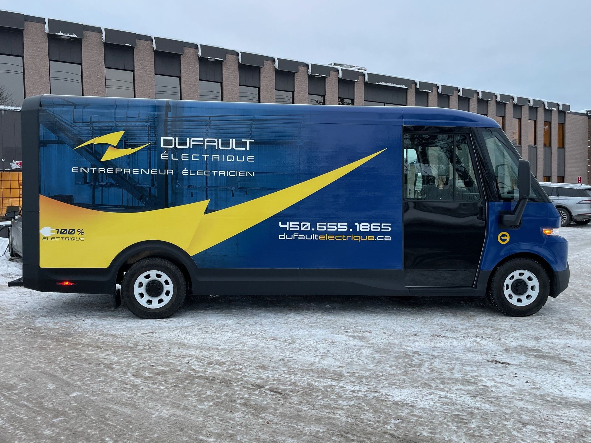 A blue and yellow van is parked in the snow in front of a building.