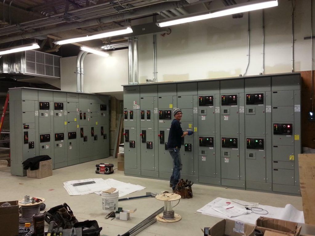 A man is working on electrical panels in a room.