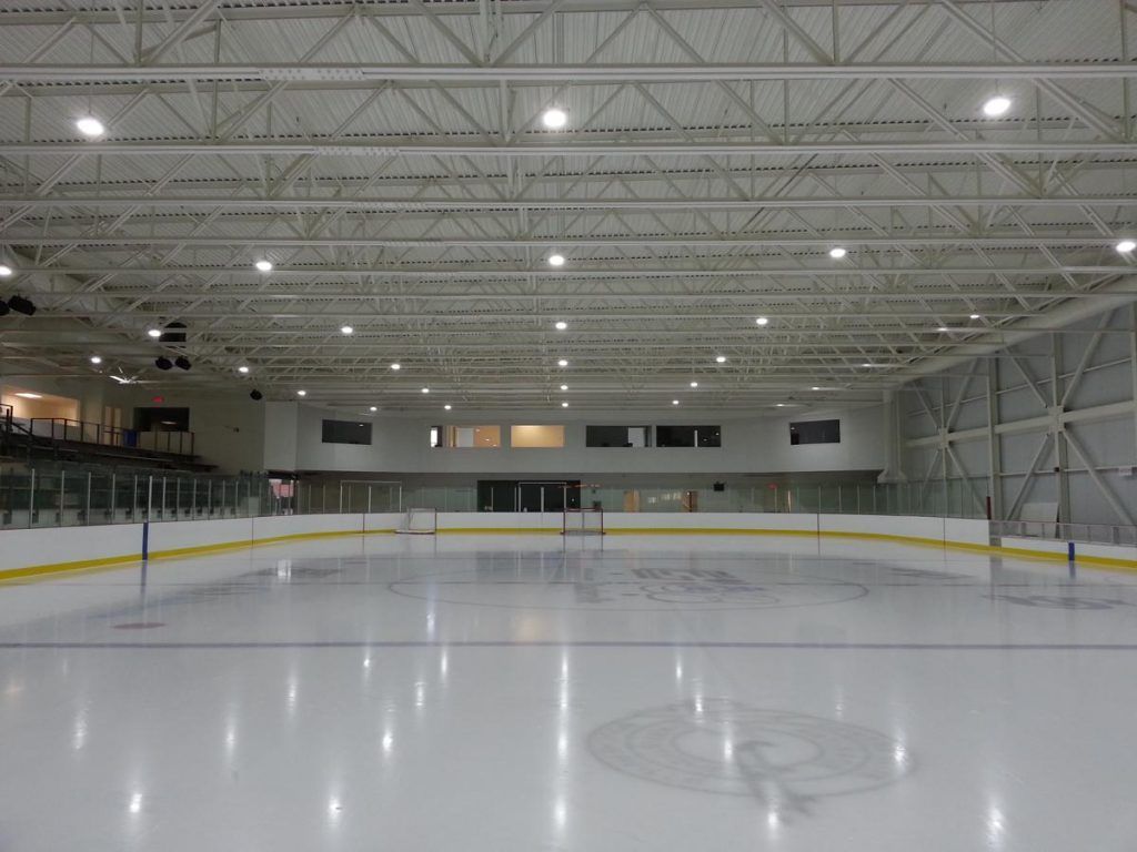 A large indoor ice rink with a logo on the ice.