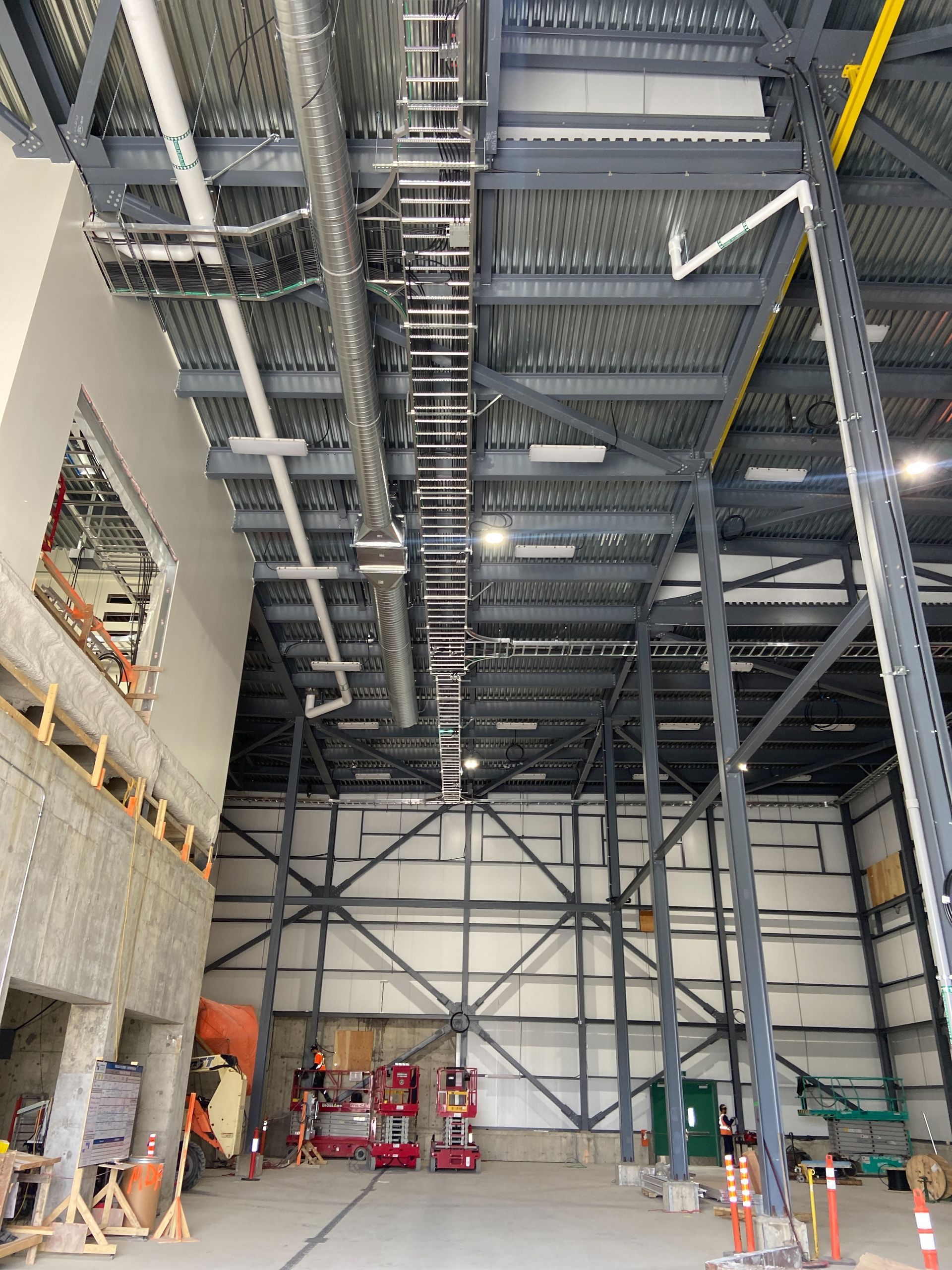 A large warehouse with a lot of pipes hanging from the ceiling.
