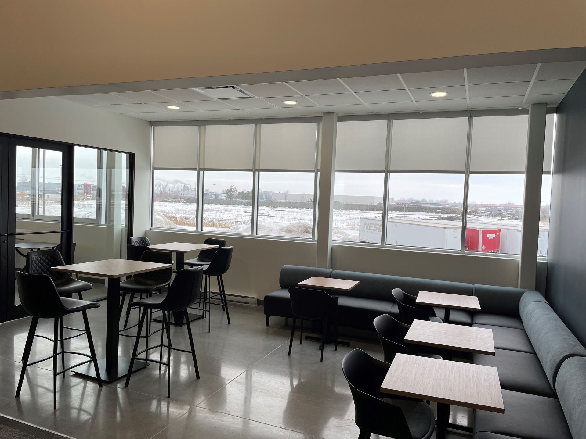 A room with tables and chairs and a large window.