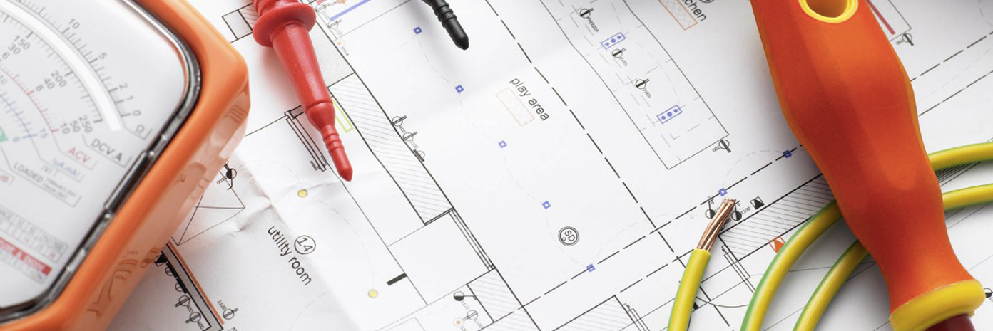 Les outils d'un électricien sont posés sur un plan.