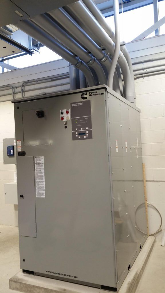 A large electrical box is sitting on top of a concrete platform in a room.