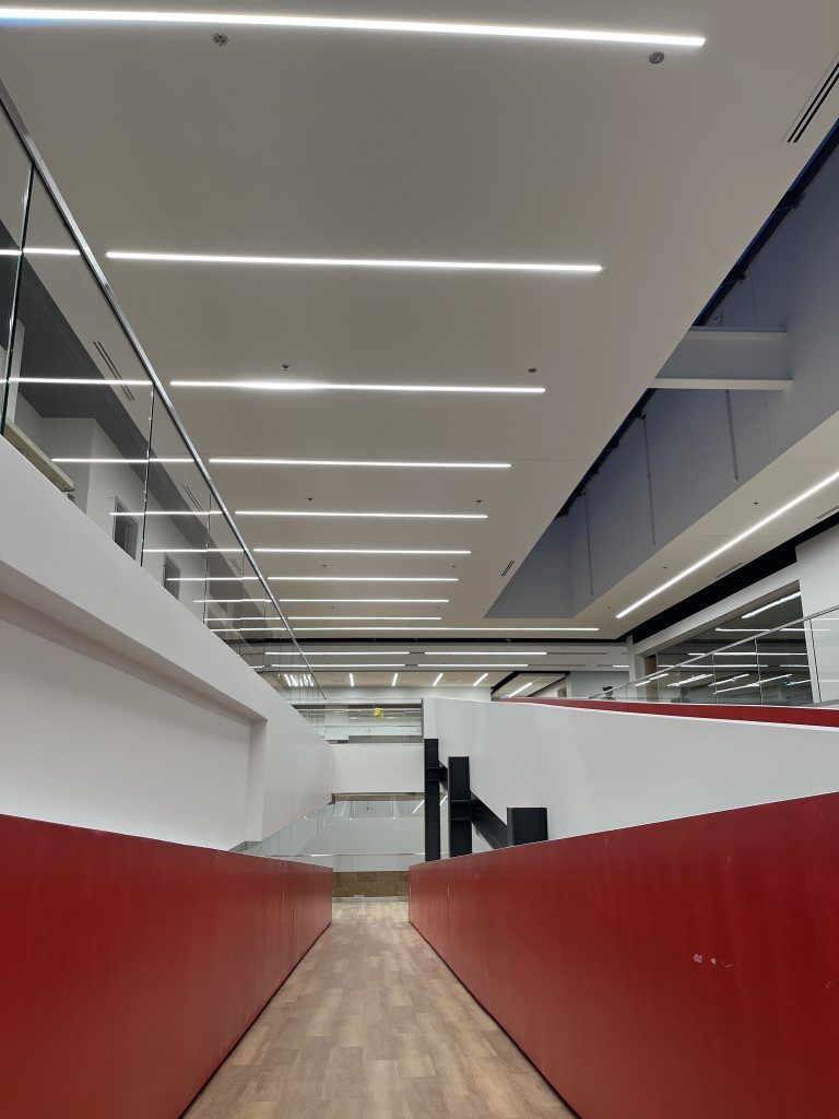 A long hallway with red walls and a ceiling with a lot of lights