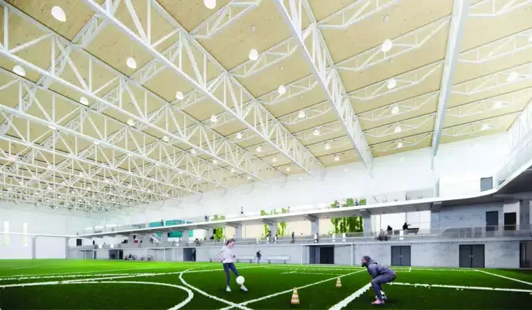 Two people are playing soccer in a large indoor stadium.