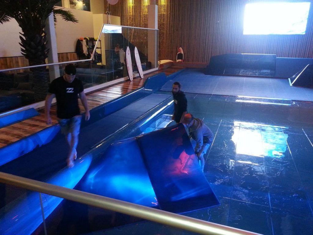A group of people are standing in a pool with blue lights on it