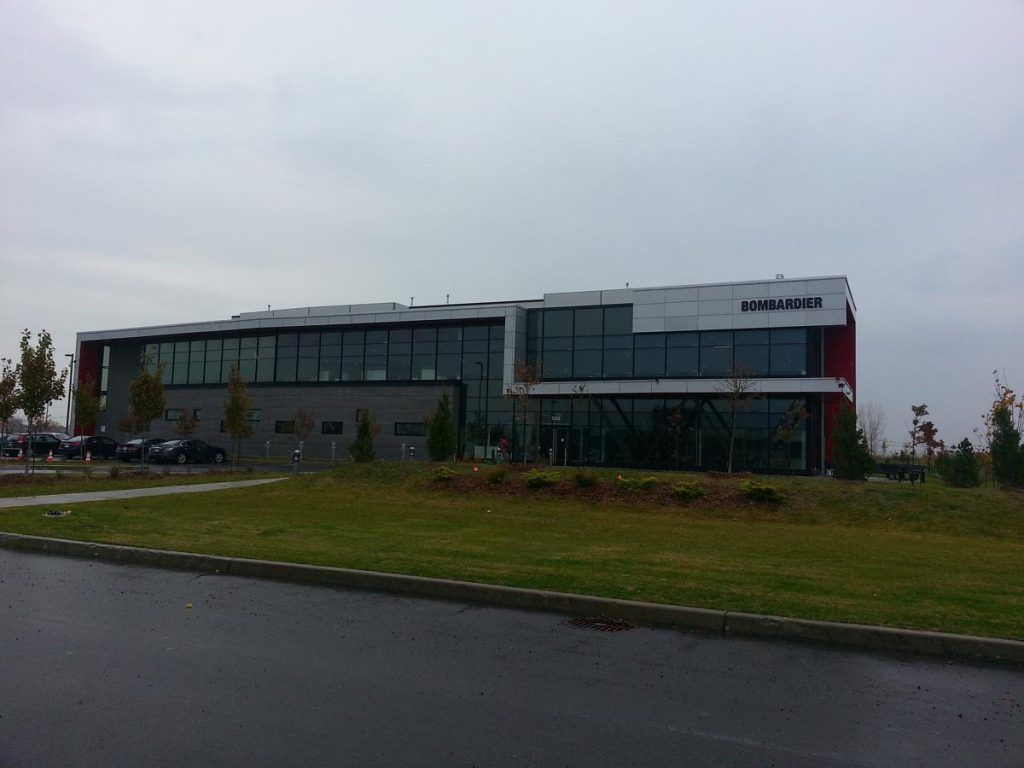 A large building with a lot of windows is sitting in the middle of a grassy field.