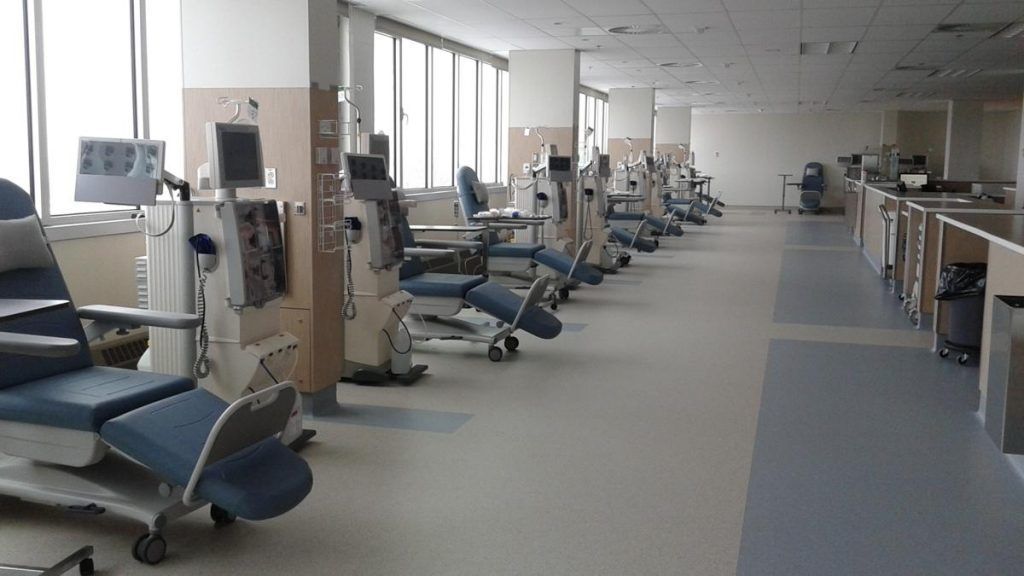 A row of dialysis machines are lined up in a hospital room.